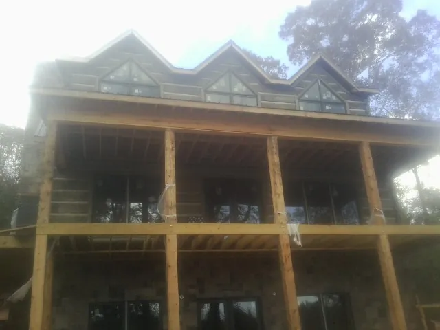 Dormers and porch framing on a large log home under construction — Roof Coating work by our crew in Florahome