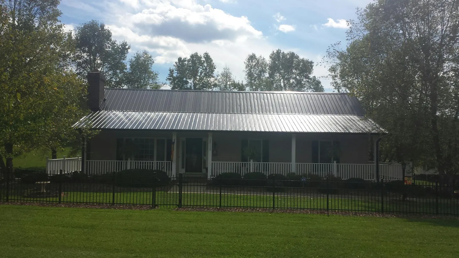 Gray metal roof on a brick ranch with a full width front porch — Gutter Guard Installation work by our crew in Florahome
