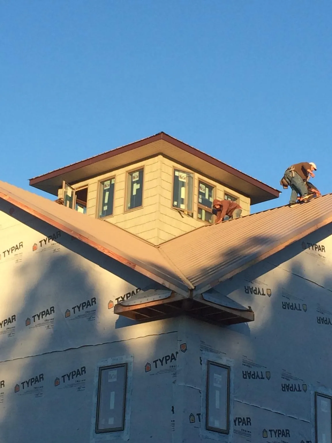 Roofers working around a rooftop cupola on a new metal roof at sunset — Roof Waterproofing in Florahome by Roofing Brothers